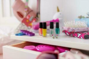 mess in the little girl's room. Nightstand with pink accessories close-up photo