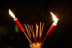 burning Incense and red candles to pay homage on a dark background during Hungry Ghost Festival pay homage to their deceased ancestors photo