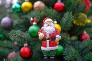 Toy Santa Claus among Christmas tree branches decorated with shiny Christmas balls. . photo