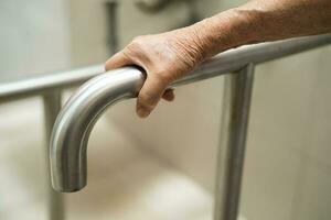 Asian elderly woman patient use toilet bathroom handle security in nursing hospital, healthy strong medical concept. photo