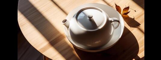 Top view of minimalist white ceramic teapot on wooden table under the sun, negative space. photo