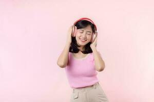 Smile pretty model person listen music song and enjoy dance with wireless headphone online audio radio sound. Positive fun exited joyful youth female woman sing on pink isolated background studio photo