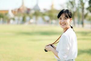 Portrait of asian woman traveler using camera. Asia summer tourism vacation concept with the grand palace in a background at Bangkok, Thailand photo