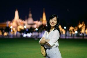 Portrait young beautiful asian woman smiling while travel at Temple of the Emerald Buddha or Wat Phra Kaew in night view point, Bangkok, Thailand. photo