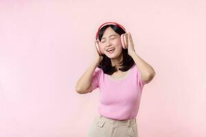 Smile pretty model person listen music song and enjoy dance with wireless headphone online audio radio sound. Positive fun exited joyful youth female woman sing on pink isolated background studio photo