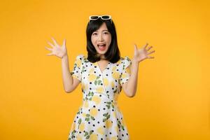 Portrait young excited attractive confident asian woman surprised and opened mouth standing with springtime dress isolated on yellow background. photo