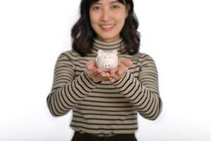 Portrait of young Asian woman casual uniform holding white piggy bank isolated on white background, Financial and bank saving money concept photo