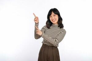 Beautiful young Asian woman on sweater cloth pointing up to copy space and looking at camera with smile face and happy isolated on white background photo