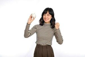 Portrait of young Asian woman casual uniform holding white piggy bank isolated on white background, Financial and bank saving money concept photo