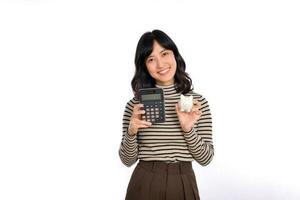 retrato de joven asiático mujer casual uniforme participación blanco cerdito banco y calculadora aislado en blanco fondo, financiero y banco ahorro dinero concepto foto