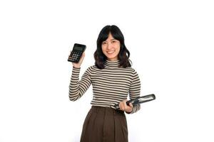 Portrait of young Asian woman casual uniform holding white piggy bank and notebook isolated on white background. Financial and bank saving money concept photo