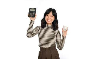 Portrait of young Asian woman casual uniform holding white piggy bank and calculator isolated on white background, Financial and bank saving money concept photo