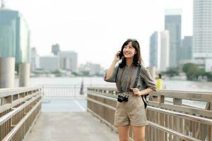 Young Asian woman backpack traveler using mobile phone in express boat pier on Chao Phraya River in Bangkok. photo