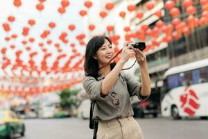 Young Asian woman backpack traveler enjoying China town street food market in Bangkok, Thailand. Traveler checking out side streets. photo