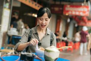 contento joven asiático mujer mochila viajero disfrutando calle comida a China pueblo calle comida mercado en bangkok, tailandia viajero comprobación fuera lado calles foto