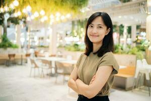 Smiling beautiful asian woman standing in cafeteria at shopping mall. photo
