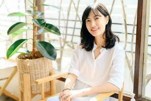 Brightly smiling beautiful young asian woman sitting in coffee cafe in sunny day photo