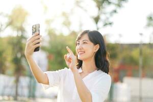 Portrait beautiful young asian woman with smart mobile phone around outdoor nature view in a sunny summer day photo