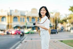 Portrait beautiful asian woman traveler with camera explore street on summer vacation in Bangkok, Thailand photo