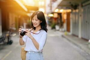 Portrait of asian woman traveler using camera at street of Bangkok, Thailand. Asia summer tourism vacation concept photo