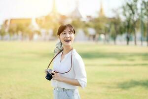 Portrait of asian woman traveler using camera. Asia summer tourism vacation concept with the grand palace in a background at Bangkok, Thailand photo