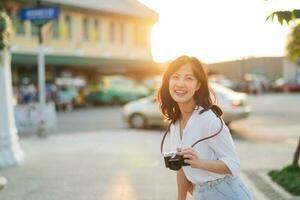 Portrait of asian woman traveler using camera at street of Bangkok, Thailand. Asia summer tourism vacation concept photo