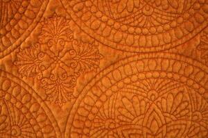 Close Up of Orange Colored Quilted Fabric photo