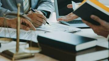 Business and lawyers discussing contract papers with brass scale on desk in office. Law, legal services, advice, justice and law concept picture with film grain effect video