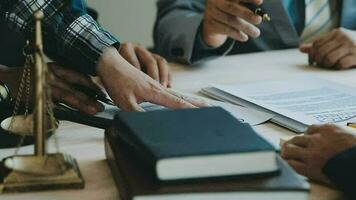 Business and lawyers discussing contract papers with brass scale on desk in office. Law, legal services, advice, justice and law concept picture with film grain effect video