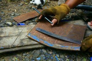 a hand is using a pencil and a ruler to measure the rusted iron to be cut photo