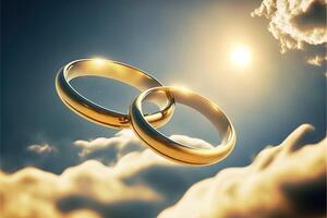 A pair of gold wedding rings floating in the sky. two wedding rings floating in the clouds with a sun in the background and a blue sky with clouds below them. . Wedding concept. photo