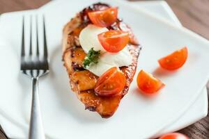 Grilled chicken steak with mozzarella and cherry tomatoes photo