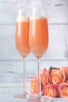 Two glasses of bellini cocktail with bouquet of roses photo