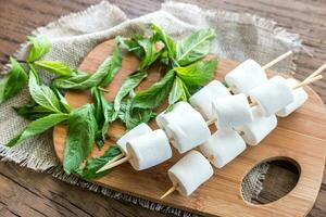 Marshmallow skewers on the wooden board photo