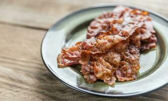 Stack of fried bacon strips on the plate photo