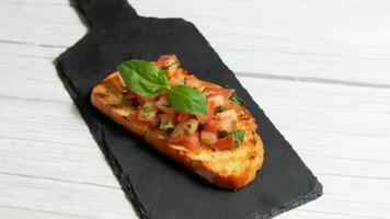 Bruschetta en un negro lámina, en un blanco de madera antecedentes foto