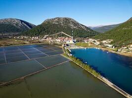 Aerial drone view of the salt pan in the city of Ston in Croatia. Fortified walls in the hills in the background. Salt fields. Ston Salt Works. Tourism near the Adriatic sea. Historic visits. photo
