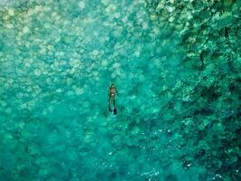 aéreo zumbido ver de un persona haciendo pesca submarina en cristal azul agua. recreativo pescar y verano actividad. Hora de verano. foto