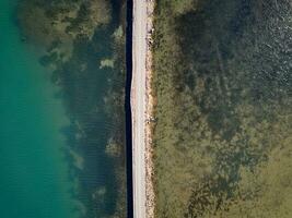 Road passing through the lake. Travel and explore concept. Road in between water. Aerial drone view. photo