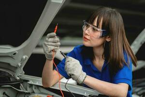 female car mechanic checking the engine of a car. A mechanic inspects and maintains the engine of a car or vehicle. A female car mechanic checking the engine of a car. car mechanic concept photo