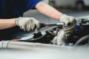 Close-up, a car mechanic checking the oil in a car's engine. Technician inspecting and maintaining the engine of a car or vehicle. Female car mechanic checking car engine photo