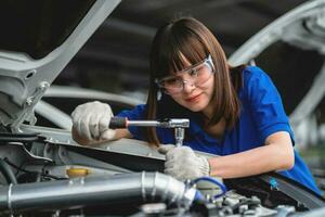 Professional service concept. Professional Asian female mechanic checking and repairing car bonnet in garage at garage car mechanic car maintenance concept photo