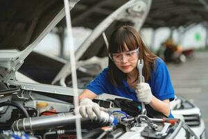 Professional service concept. Professional Asian female mechanic checking and repairing car bonnet in garage at garage car mechanic car maintenance concept photo