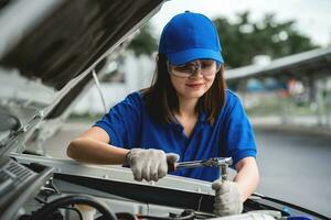 profesional asiático hembra mecánico inspecciona y refacción carros y mantiene carros. concepto de coche Servicio y mantenimiento. auto mecánico. auto mecánico. foto