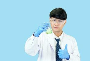 asiático hombre estudiante científico o médico uno persona, vistiendo un blanco vestido, de pie, mirando y sonriente, azul antecedentes con un estetoscopio auscultando el corazón alrededor su cuello. foto