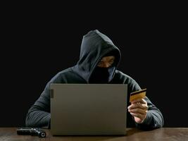 Hacker spy man one person in black hoodie sitting on a table looking computer laptop used login password attack security to circulate data digital in internet network system, night dark background. photo