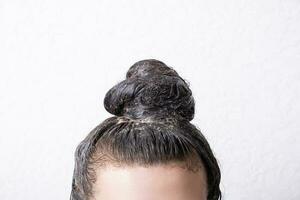 Women's hair is collected in a bun with paint applied to it. Hair dyeing concept photo