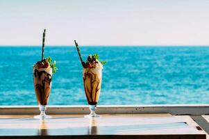 Two delicious sundays on a table overlooking the ocean on a sunny day photo