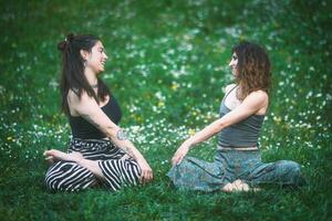 Couple of young women look at each other during a yoga session photo