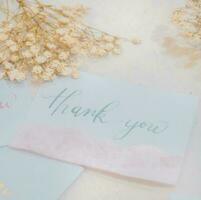 A white card with gold lettering that says thank you on it. photo